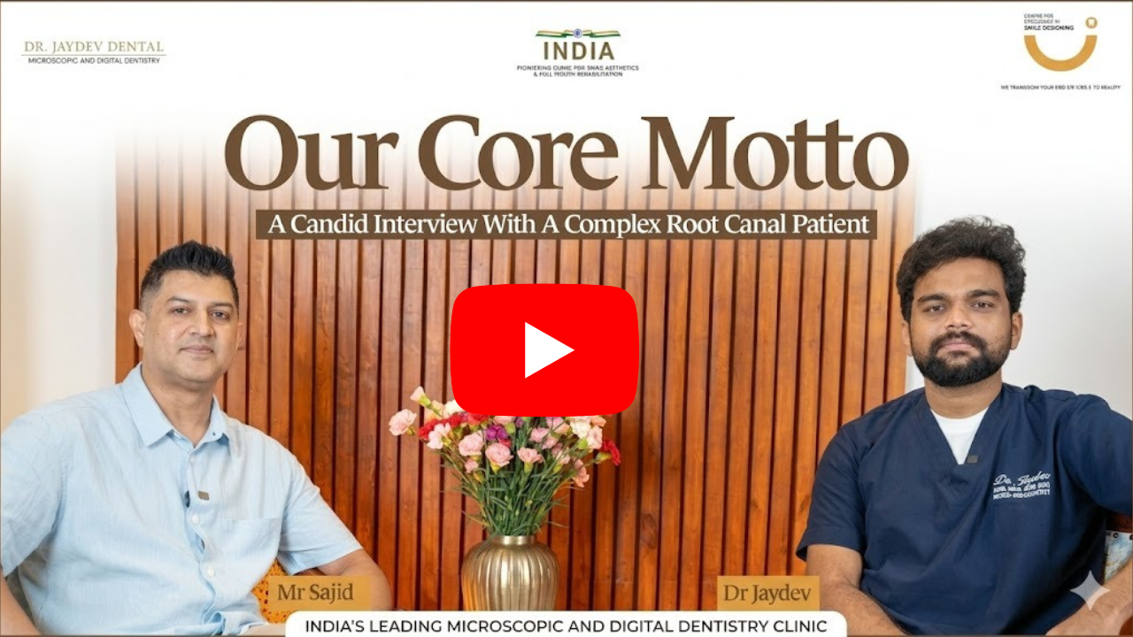 Video thumbnail for 'Our Core Motto' showing a dentist and patient seated before a wooden backdrop with a vase of flowers; YouTube play button overlay.