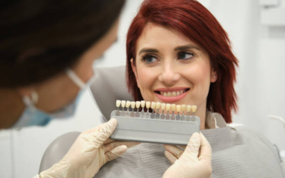 Dentist shows a dental model of teeth to a smiling patient in a clinic, hands wearing gloves holding the model between them.