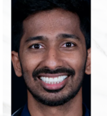 Close-up portrait of a man with short dark hair and a trimmed beard smiling at the camera.